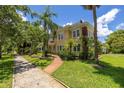 Beautiful two-story yellow home featuring a brick path, well-manicured lawn, and mature trees at 635 Bay Ne St, St Petersburg, FL 33701