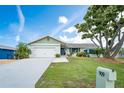 Charming single-story home with a well-maintained lawn, mature shade tree, and an attached two-car garage at 909 Silver Palm Way, Apollo Beach, FL 33572