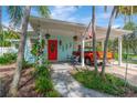 The home features a welcoming front porch with rocking chairs, a vibrant red door, and quaint decor at 1042 S Sterling Ave, Tampa, FL 33629