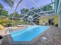 Sparkling in-ground pool with a screened enclosure, surrounded by a brick patio and lush landscaping at 1358 Forestedge Blvd, Oldsmar, FL 34677
