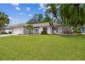 Single-story home with mature landscaping, large front lawn, and two-car garage at 18504 Putters Pl, Tampa, FL 33647