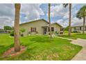 Charming home exterior features a large, well-maintained lawn with mature palm trees and landscaping at 1905 Canterbury Ln # 17, Sun City Center, FL 33573