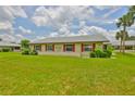 Charming home exterior features a large, well-maintained lawn and mature landscaping with red shutters on the windows at 1905 Canterbury Ln # 17, Sun City Center, FL 33573