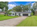 Single story home boasts a well-maintained lawn, stone facade, and a long driveway at 210 Lake Hobbs Rd, Lutz, FL 33548