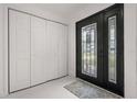 Bright foyer featuring sleek white tile flooring, a modern front door, and a spacious coat closet at 210 Lake Hobbs Rd, Lutz, FL 33548