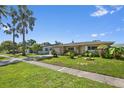 Inviting single-story home with a tidy front lawn, mature palm trees, and lush garden at 2518 Keen Park Dr, Largo, FL 33771