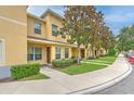 Well-maintained townhome featuring manicured lawns, mature trees, and a welcoming entryway at 6332 Timberly Ln, Zephyrhills, FL 33542