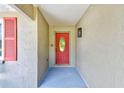 Covered entryway featuring a vibrant red front door and textured walls at 8402 Roxboro Dr, Hudson, FL 34667