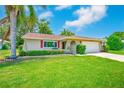 Charming single-story home featuring a lush green lawn, vibrant landscaping, and a bright red front door at 8402 Roxboro Dr, Hudson, FL 34667
