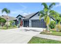 Inviting home showcasing a well-maintained lawn, mature trees, and a spacious driveway leading to a two-car garage at 10813 Rockledge View Dr., Riverview, FL 33579