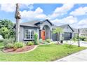 Landscaped front yard featuring lush green grass, palm trees, and colorful flowerbeds enhancing curb appeal at 10813 Rockledge View Dr., Riverview, FL 33579