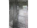 Bathroom shower with frameless glass doors, shower-head, pebble floor, and neutral tile walls at 10918 N Boulevard, Tampa, FL 33612