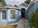 Inviting front entry with a walkway leading to the front door and large windows at 12216 Southbridge Ter, Hudson, FL 34669