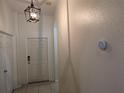 Hallway with neutral walls, tiled floors, featuring modern lighting and digital thermostat at 12216 Southbridge Ter, Hudson, FL 34669