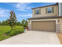 Daytime view of a two-story home showcasing a two-car garage, stone accents, and landscaped front yard at 17741 Tawny Malt Pl, Land O Lakes, FL 34638
