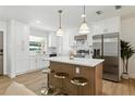 Modern kitchen with stainless steel appliances, island with seating, white cabinetry and pendant lighting at 4611 W Bay Court Avenue, Tampa, FL 33611