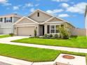 Inviting single-story home with a well-kept lawn, front garden, and a convenient two-car garage at 5474 Flint Hills Dr, Wimauma, FL 33598
