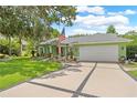 View of the green house with a wide driveway leading to the garage, American flag at 1271 Candlelight Blvd, Brooksville, FL 34601