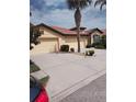 Charming home featuring a red tile roof, three-car garage, a mature palm tree and lush landscaping at 5473 Sunset Falls Dr, Apollo Beach, FL 33572
