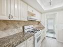 Bright kitchen featuring granite countertops, tile backsplash, and white appliances at 6015 19Th N St # 117, St Petersburg, FL 33714