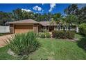 Inviting home showcasing lush green lawn, mature palm trees, and attractive brick accents at 11279 Oakridge Trl, Seminole, FL 33772