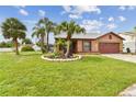 A cozy single-story home with a lush green lawn, complemented by swaying palm trees and vibrant landscaping at 11304 Plumtree Ct, Riverview, FL 33579