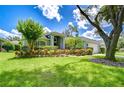 Beautifully landscaped home featuring a lush green lawn, mature trees, and colorful flowering bushes at 15126 Shearcrest Dr, Lithia, FL 33547