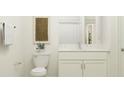 Bright bathroom features a white vanity, a modern faucet, and an above-toilet woven art piece at 31639 Splash Isle, San Antonio, FL 33576