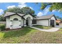 Attractive home featuring a well-manicured lawn and a two-car garage, set against a backdrop of trees at 5092 Abagail Dr, Spring Hill, FL 34608