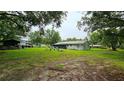 Large backyard with mature trees, a screened in porch, fire pit, and plenty of room for outdoor activities at 5623 Southernview Dr, Zephyrhills, FL 33541
