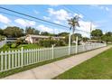 Lovely home with a white picket fence, green lawn, landscaping, and clear blue skies at 1453 Belleair Rd, Clearwater, FL 33756
