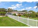 Quaint single-story home showcasing a neatly fenced yard and lush landscaping under a sunny sky at 1453 Belleair Rd, Clearwater, FL 33756
