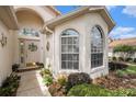 Inviting front entrance with arched windows, a decorative door, and colorful landscaping at 371 Quane Ave, Spring Hill, FL 34609