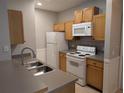 Kitchen with stainless steel sink, white appliances, light wood cabinets, and grey countertops at 4207 S Dale Mabry Hwy # 6212, Tampa, FL 33611