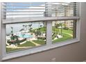 A stunning pool and waterfront view from a window with white blinds and a marble windowsill at 5108 Brittany S Dr # 405, St Petersburg, FL 33715