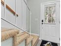 Staircase featuring carpeted steps, white railing, and a view of the front door and landing at 12336 Villager Ct, Tampa, FL 33625