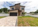 Modern two-story house with paver driveway, sleek black garage door, and minimalist landscaping at 1808 W Erna Dr, Tampa, FL 33603