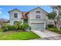 Charming two-story home with a two-car garage, lush lawn, tropical landscaping, and neutral color scheme at 9707 Kings Canyon Pl, Tampa, FL 33634