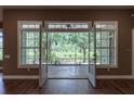 Living room with French doors opening to screened lanai with view of green backyard at 1137 Pristine Pl, Lutz, FL 33549