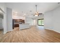 Open concept living room showcases wood tile floors, a ceiling fan and transitions into the kitchen at 12117 Streambed Dr, Riverview, FL 33579