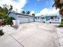 Inviting blue home showcasing a well-maintained lawn, a two car garage, and a cozy front porch at 15817 Redington Dr, Redington Beach, FL 33708