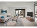 Bright, staged living room with modern decor, plush seating, and a sliding glass door to the outside at 358 Moorings Cove Dr # 4B, Tarpon Springs, FL 34689