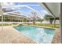 Relaxing screened-in pool area with a waterfall feature, surrounded by a well-maintained backyard at 7607 New York Ave, Hudson, FL 34667
