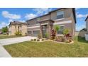 Two-story home featuring a three-car garage, stone accents, and beautifully landscaped front yard at 9456 Channing Hill Dr, Sun City Center, FL 33573