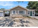 Charming single-story home featuring a covered parking, inviting green door, and lovely front garden at 1432 San Juan Ct, Clearwater, FL 33756