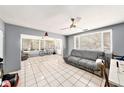 Bright living room boasts tile flooring, ceiling fan, and large windows with blinds, filling the space with light at 1432 San Juan Ct, Clearwater, FL 33756