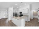 Modern white kitchen with a center island, stainless steel appliances, and granite countertops at 16313 Scaup Duck Ave, Brooksville, FL 34614