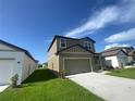 A two-story home featuring gray siding, a two-car garage, well-maintained lawn, and simple landscaping at 35233 White Water Lily Way, Zephyrhills, FL 33541