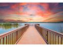Scenic view of a wooden dock extending into a tranquil lake under a vibrant, colorful sky at 7903 Seminole Blvd # 2203, Seminole, FL 33772