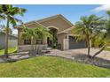 Landscaped yard features palm trees and decorative rocks, leading up to this home's inviting front entrance at 8620 Sandy Plains Dr, Riverview, FL 33578